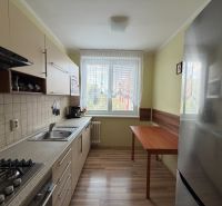 A kitchen in a 3-room apartment with a wooden decor floor and a kitchen unit.