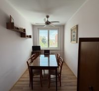 A dining room with a wooden table, chairs, and a floor with a wooden decor in a 3-room apartment.