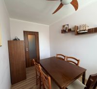 Dining room in a 3-room apartment with a wooden table and shelves.