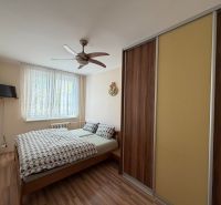 Bedroom in a 3-room apartment with a bed, wardrobe, and floor with wooden decor.