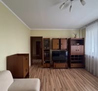 Living room in a three-room apartment with furniture and flooring featuring a wooden decor.