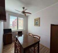 Dining area in a 3-room apartment with a wooden table and floor with a wooden decor.