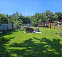 Mowed lawn in the gardens at Kamenný mlyn in Trnava, surrounded by trees.