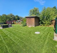 Grassy gardens in Kamenný mlyn in Trnava with a wooden shelter and a trampoline.