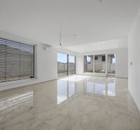 Spacious living area in a family house with large windows and glossy tiles.