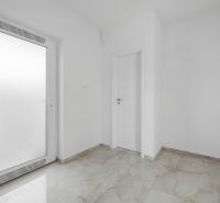 White entrance room in a family house with tiles and doors.