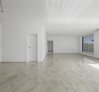 A spacious room with a large window and a wooden decor floor in a family house.