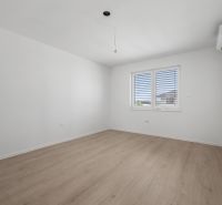 An empty room with white walls, a wooden decor floor, and air conditioning in a family house.