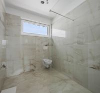 Bathroom of a family house with walls and floor in tiles of light shades.