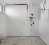 A white room with a boiler and a wooden-patterned floor in a family house.