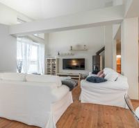 Recreational apartment with white sofas and a wooden decor floor, bright environment.