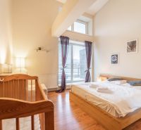 Bright bedroom in a holiday apartment with a crib and wood-patterned flooring.