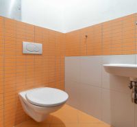 Bathroom in a holiday apartment with orange tiles and a wall-mounted toilet.