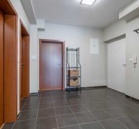 Entrance hall of a holiday apartment with dark tiles, wooden doors, and a coat rack.