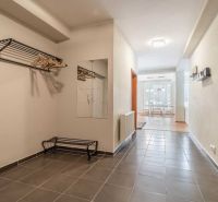 Hallway of a recreational apartment with tiles, a mirror, and a coat rack.