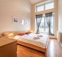 A bright bedroom with a double bed and a wooden decor floor in a holiday apartment.