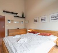 Bright bedroom in a holiday apartment with wood-patterned flooring and simple furnishings.