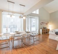 Recreational apartment with a dining table, comfortable sofas, and a wooden decor floor.