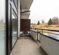 The balcony of a recreational apartment in Donovaly with a view of nature and cottages.