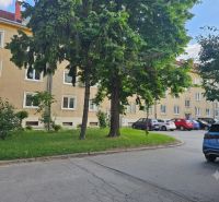 Parking lot near 3-room apartments on Študentská Street in Trnava, surrounded by greenery and trees.