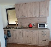 A kitchen with a wooden decor floor, cabinets with wooden decor, and appliances.