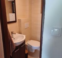 A bathroom in a cabin with a sink, toilet, and light tiles.