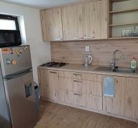 A kitchen unit with a wooden decor floor and appliances in a cottage.