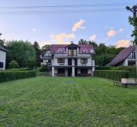 A cottage in Kaluža surrounded by greenery, maintained lawn, surroundings with trees, blue sky.