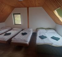 A bedroom in a cottage with three beds and a wooden decor floor.