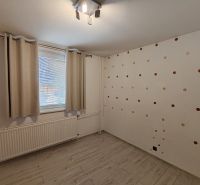 A room in a 3-room apartment with a wooden decor floor and dotted wallpaper.