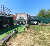 The garden of a family house in Divín with a gazebo, a swing, and a green lawn.