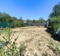 A garden at a family house in Divín with a lawn and flowers, surrounded by a hedge.