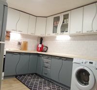 A kitchen in a family house with white and gray cabinets, a floor with a wooden decor.
