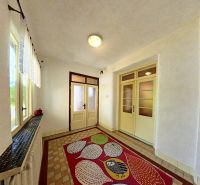 A hallway in a family house with a colorful carpet and glass doors.