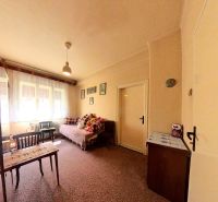 A room in a family house with a carpeted floor, a bed, furniture, and toys on the bed.