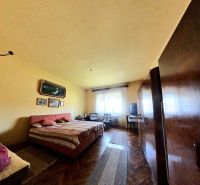 Bedroom in a family house with a wooden decor floor, bed, wardrobes, paintings on the wall.