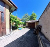 Courtyards of family houses on Sládkovičova Street in Zlaté Moravce surrounded by greenery and paved with tiles.