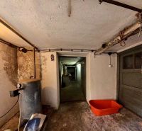 The basement of a family house with a tank and an orange plastic container on the floor.