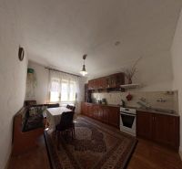A kitchen with built-in cabinets, a gas stove, and a wooden-patterned floor in a family house.