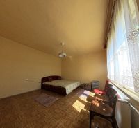 Bright room in a family house with a bed, large window, and wooden decor flooring.