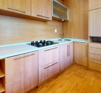 A kitchen with wooden decor, built-in appliances, and a cooktop in a 2-room apartment.