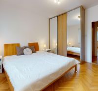Bedroom in a 2-room apartment with a wooden decor floor and a sliding wardrobe.