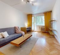 A bright living room with a sofa, a table, and a wooden decor floor in a two-room apartment.