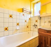 A bathroom in a family house with sunflower tiles and yellow walls.