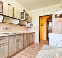 A kitchen in a family house with a tiled floor, cabinets, and a countertop.