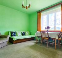 Living room in a family house with a comfortable armchair, sofa, and round table.