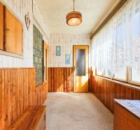 A hallway in a family house with wooden paneling and a large window with lace curtains.