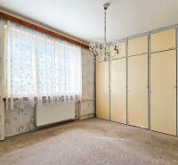 A room in a family house with a carpet, a built-in wardrobe, and delicate floral wallpaper.