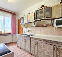 A kitchen in a family house with a colorful curtain, tiles, and a kitchen unit.