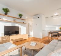 Living room in a two-room apartment with a wooden decor floor and light furniture.